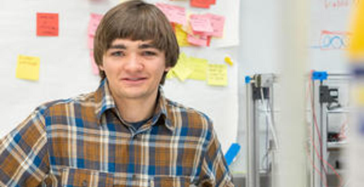 Student smiling with sticky notes in background