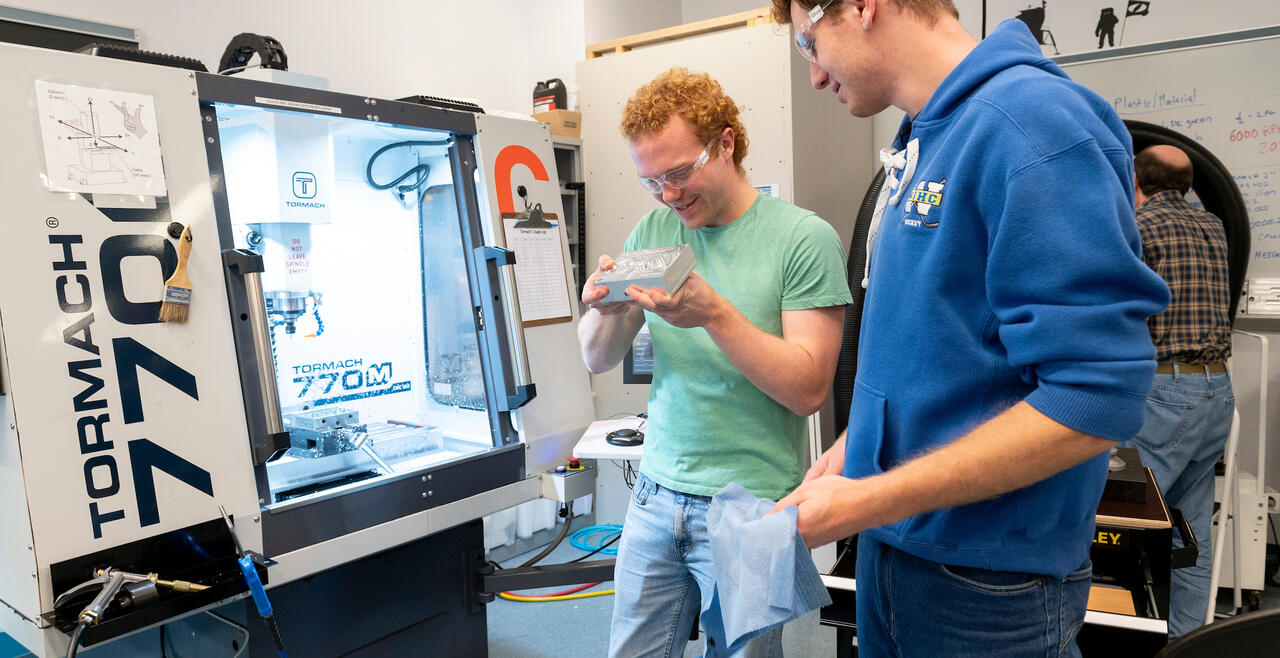 two students working on machining in the Olin Shop